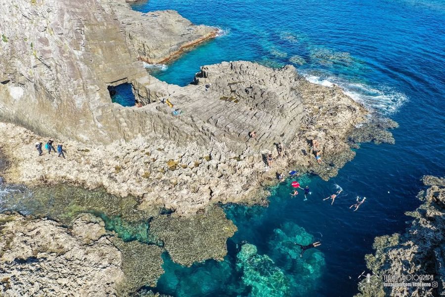 台東沖・緑島の海岸線でシュノーケラーとサンゴ礁の浅瀬を空撮