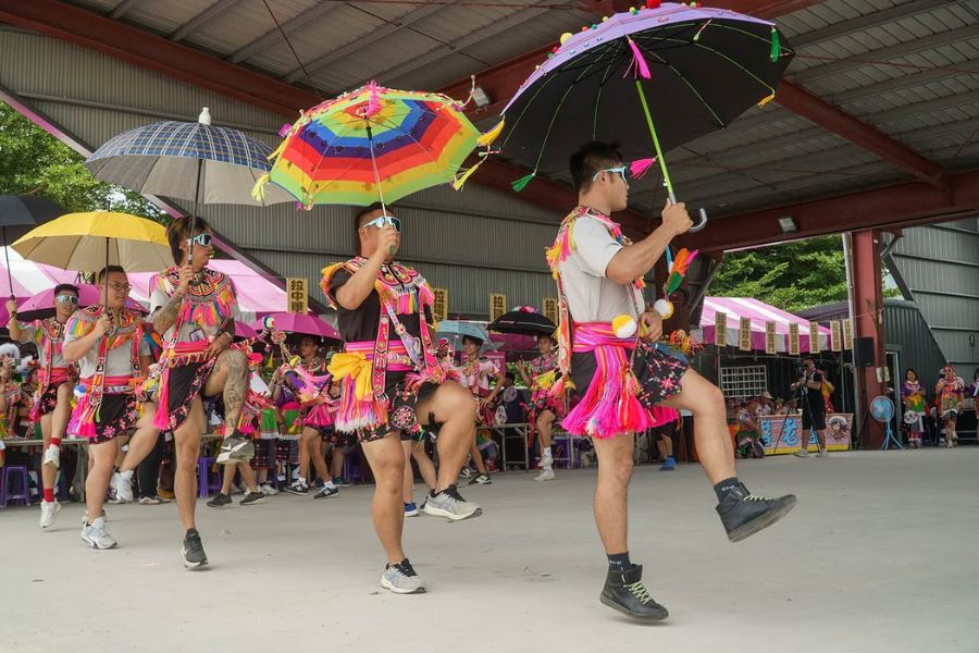 台東のアミ族祭りで色とりどりの傘を持ち屋根の下で踊る踊り手たち