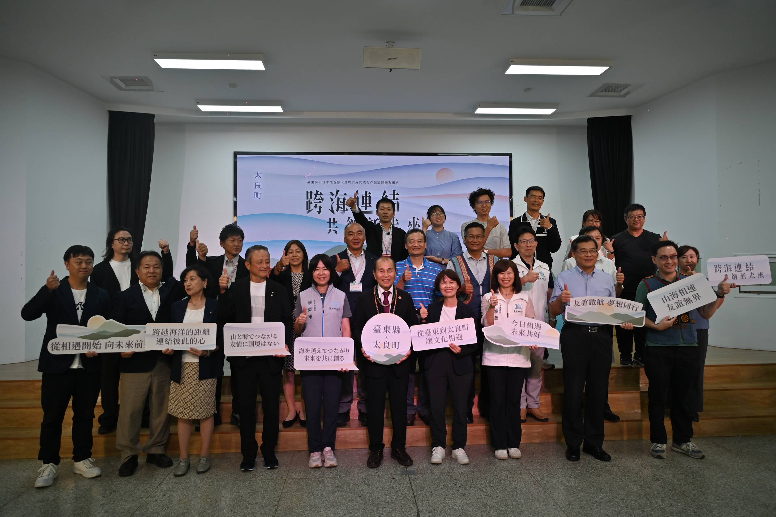 News2 B 台東県富山小学校で友好の言葉を掲げる台東県と太良町の職員・教員・生徒たちの集合写真、2026年8月