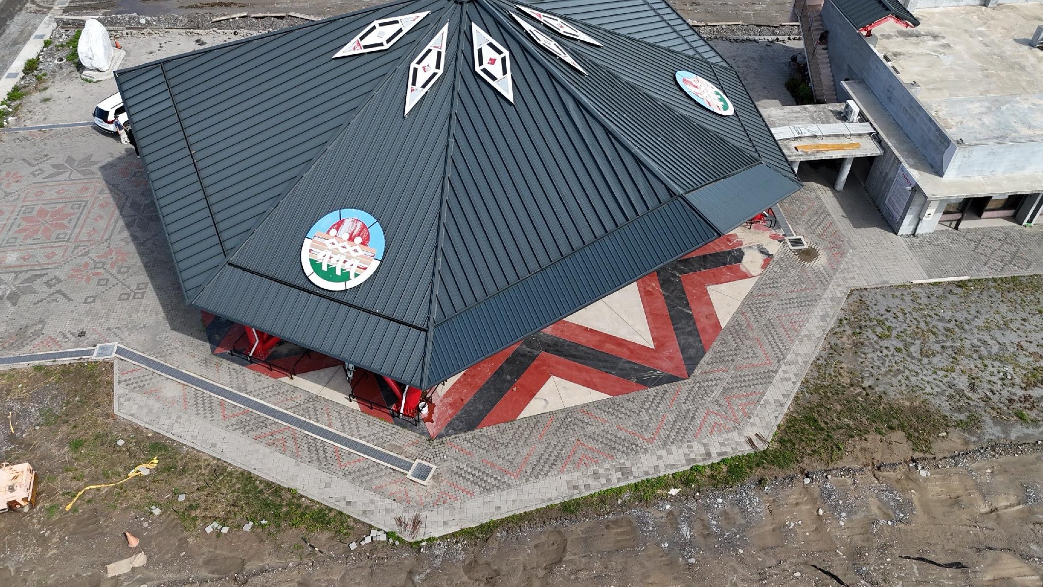 Close aerial view of the Matang Indigenous Tribal Gathering Place roof edge and red-and-black geometric plaza pattern, Taitung