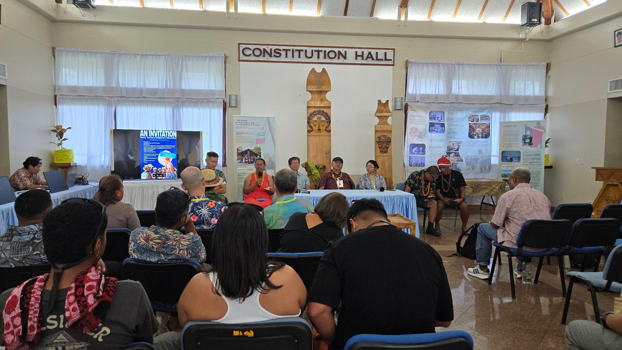 Panel discussion at Constitution Hall in Palau featuring Taiwan and Palau delegates seated before traditional carved wooden columns, September 2026