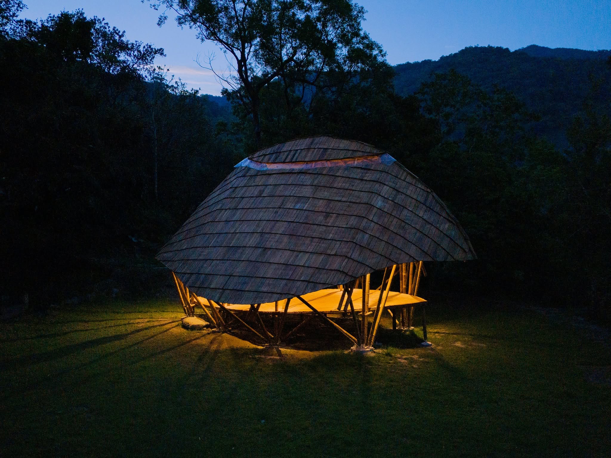 The Third Place bamboo dome glowing from within at dusk in the forest, Taitung