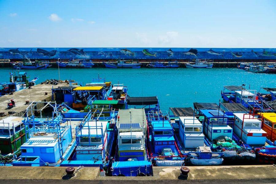 Fishing boats docked beside a painted fish mural at Fugang Fishing Harbor, Taitung