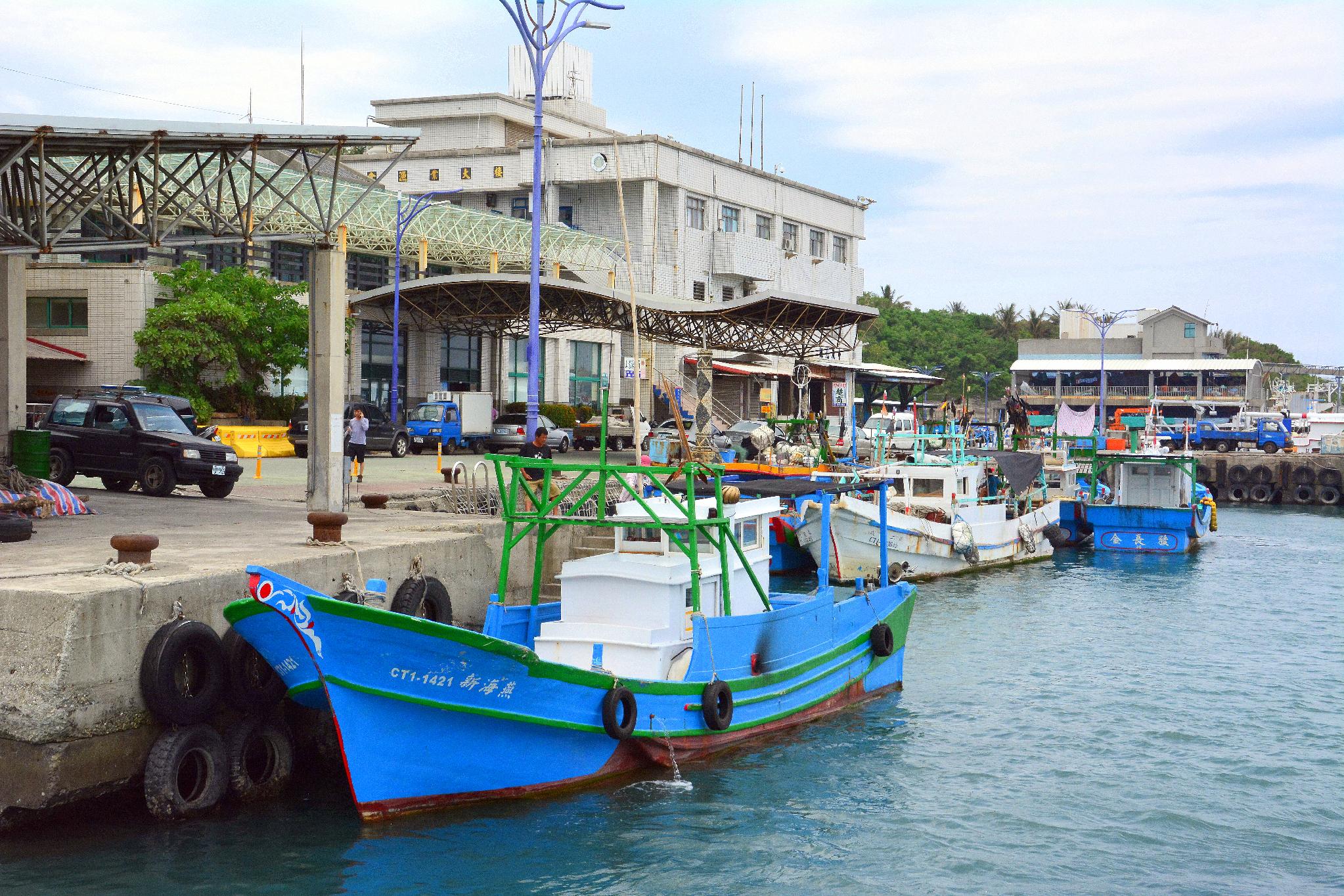 Fishing boats docked at Fugang Fishing Harbor in front of the market building, Taitung