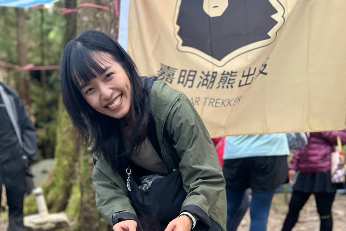 Smiling guide serving food from a large pot at a Bear Trekker mountain camp