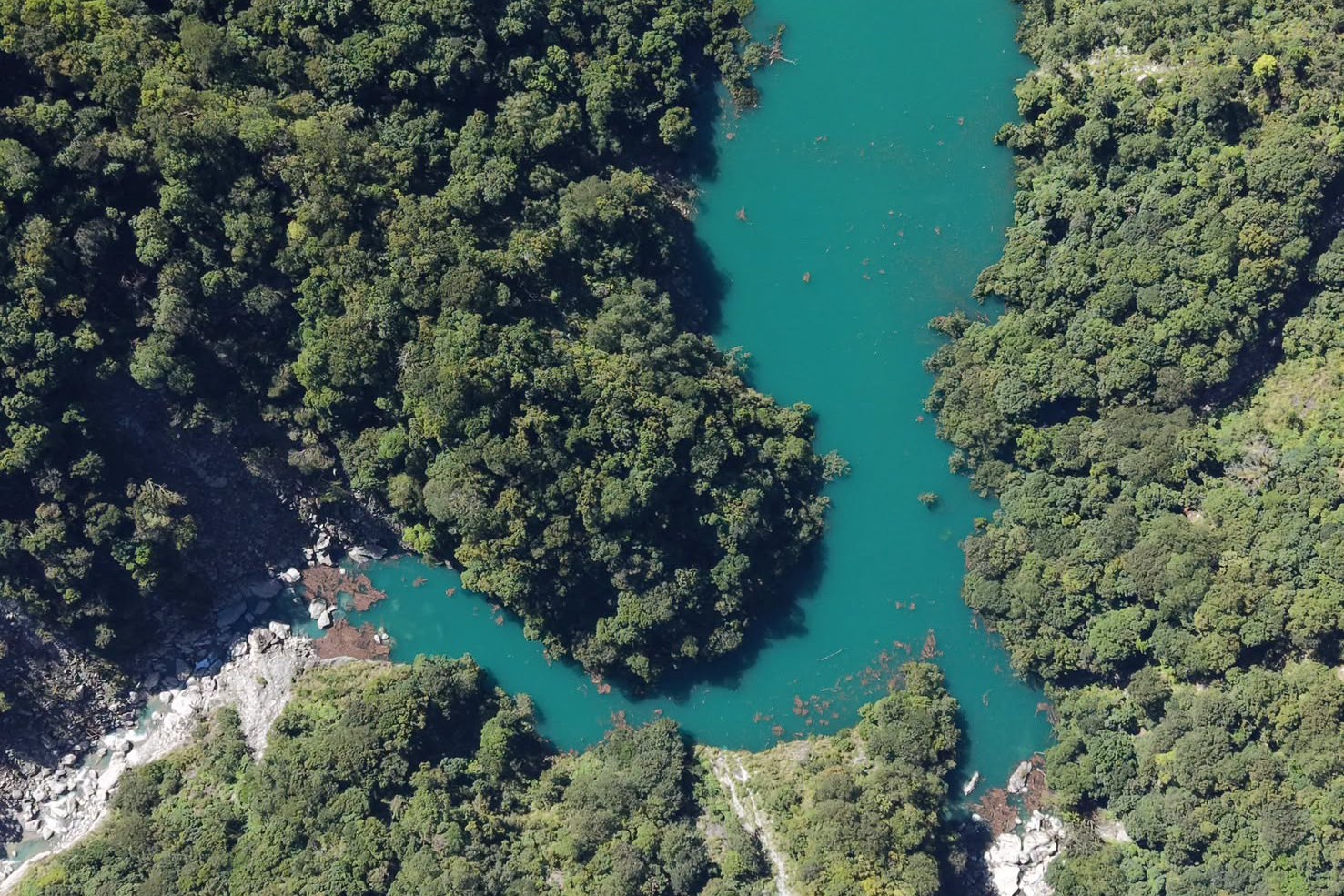 Aerial view of a turquoise river winding through forested mountains in Taitung