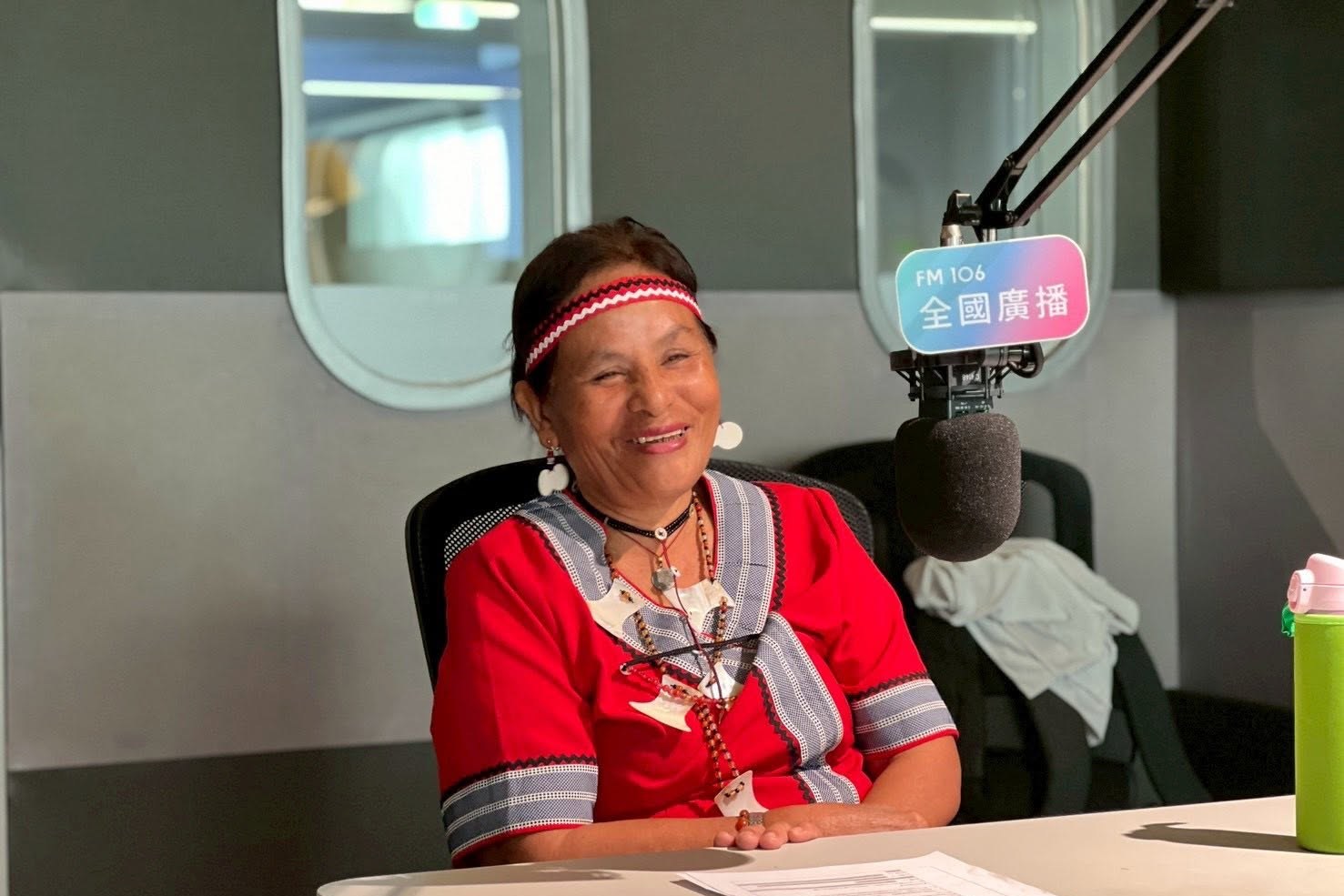 Weaving master Sinan Jiotok smiling in a radio studio in traditional Tao dress
